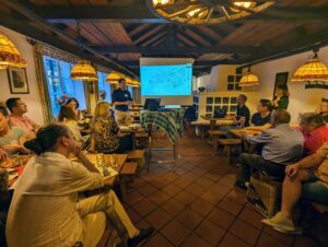 Personen sitzen in Wirtshaus und hören einen Vortrag von Architekt Florian Niedworok