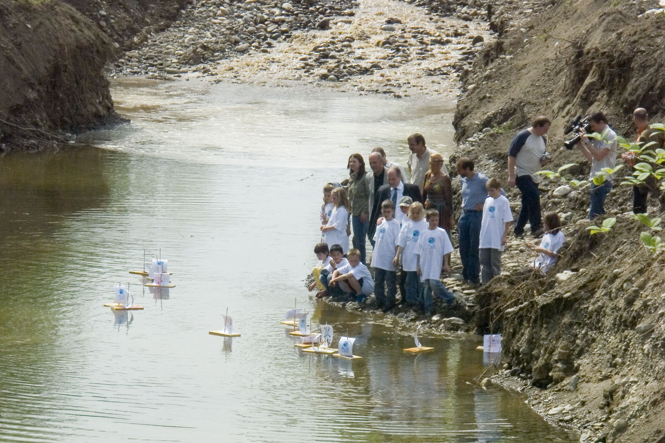 Kinder lassen Bretter als Boote am Fluss schwimmen