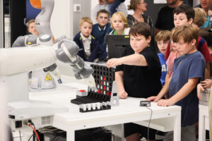 Ein Bub spielt gegen einen Roboter das Spiel Vier-Gewinnt