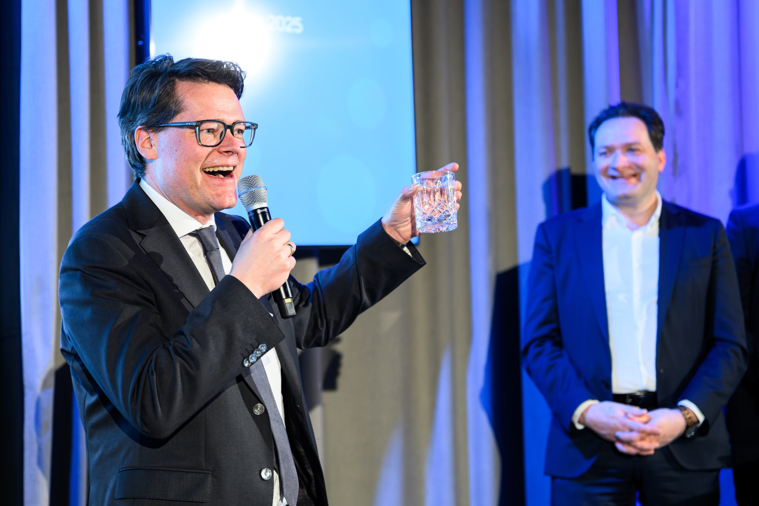 Wiener Stadtrat Jürgen Czernohorszky spricht auf Bühne und hebt Wasserglas in die Höhe