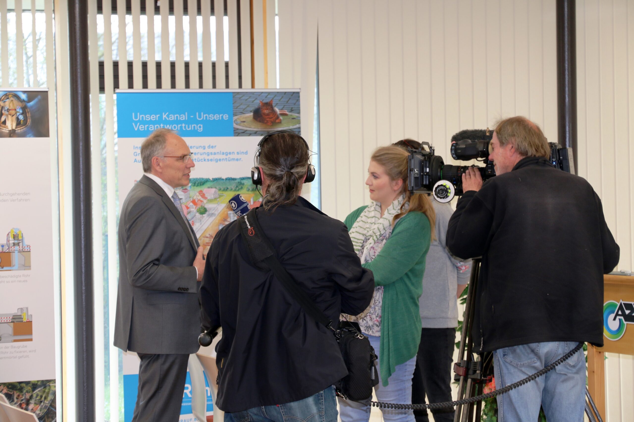 Mann wird von Fernsehkamera und Journalist:innen interviewt